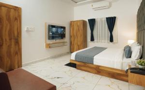 a bedroom with a bed and a tv on the wall at Hotel Maya Elite in Bhopal
