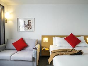 a hotel room with two beds and a couch at Novotel Glasgow Centre in Glasgow