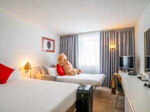 a teddy bear sitting on a bed in a hotel room at Novotel Glasgow Centre in Glasgow +125 photos