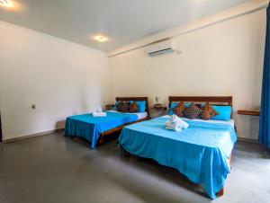 two beds in a room with blue sheets at Lily Safari Resort Udawalwa in Udawalawe