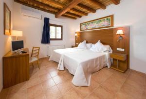 a bedroom with a bed and a desk and a television at Can Cama in Santa Gertrudis de Fruitera +54 photos