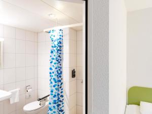 a bathroom with a shower with a blue shower curtain at ibis budget Zurich City West in Zurich +51 photos