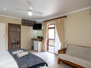 a bedroom with a bed and a couch and a television at Stonebreaker Country Lodge in Oudtshoorn