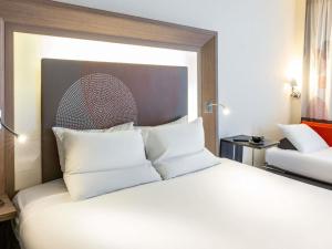 a bedroom with a large bed with white pillows at Novotel Leeds Centre in Leeds +99 photos