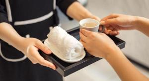 a woman holding a cup of coffee and a plate of food at Xana Hotelle·Taiyuan South Inner Ring in Taiyuan
