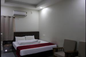 a small bedroom with a bed and a chair at SRG Shivam Residency in Tiruvannāmalai