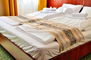 1 cama grande con sábanas blancas y almohadas. en Partium Hotel Szeged, en Szeged
