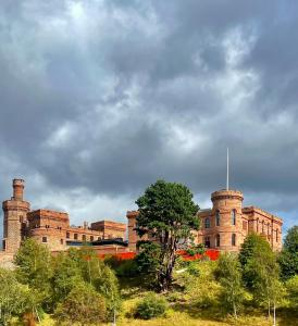 un grand bâtiment en briques avec des arbres devant lui dans l'établissement Balnakyle, à Inverness