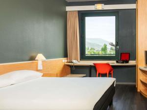 a bedroom with a bed and a red chair and a window at Hotel Ibis Firenze Prato Est in Campi Bisenzio +49 photos