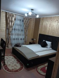 a bedroom with a bed and a window with curtains at Casuta D&M in Cisnădie