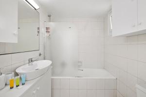 een witte badkamer met een wastafel en een douche bij Shoreline Beach House in Larnaka +21 foto's