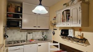 a small kitchen with white cabinets and a sink at Allgäuer Bergerlebnis mit Hallenbad in Fischen