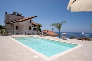 a swimming pool in front of a house with the ocean at Villa Acquamarina per Gruppi e Famiglie a Capo Vaticano Costa degli Dei in Santa Maria