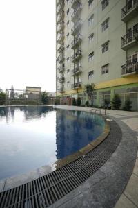 a large swimming pool in front of a building at OYO Living 3091 Apt The Suites Metro By Ananda in Bandung