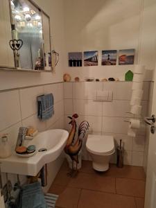 a bathroom with a sink and a toilet with a chicken on it at Ferienwohnung Rotbuche in Rastede +19 photos