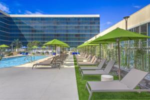 a row of lounge chairs with green umbrellas next to a pool at Hilton Anaheim in Anaheim