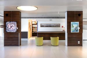 a lobby with two yellow chairs in a building at Hilton Garden Inn Venice Mestre in Mestre