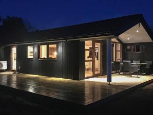 a black house with a deck at night at 6 person holiday home in Rømø in Lakolk