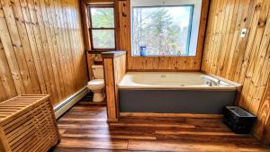 a bathroom with a tub and a toilet and a window at The Wooden Nest by AvantStay Deck Big Yard w Hammocks Fire Pit in Long Pond +27 photos