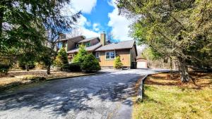 a house on a road in the woods at The Wooden Nest by AvantStay Deck Big Yard w Hammocks Fire Pit in Long Pond