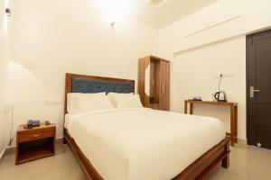 a bedroom with a large white bed and a night stand at Greens Residency in Tripunnittara
