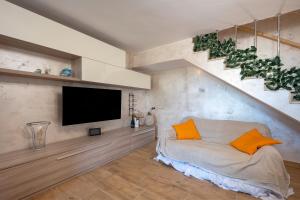 Una sala de estar con un televisor y un sofá con cojines naranjas. en Villa Marzla, en Cassano delle Murge