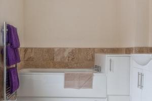 a bathroom with a tub and a sink and purple towels at Town Centre Apartment Perfect Location with on-street parking in Stratford-upon-Avon +8 photos