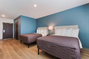 a hotel room with two beds and a blue wall at WoodSpring Suites Tamarac in Tamarac
