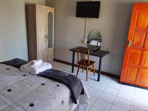 a bedroom with a bed and a desk with a chair at Phiris B&B in Esperanza