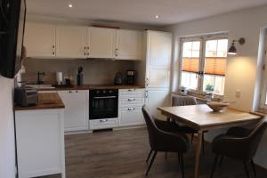 a kitchen with white cabinets and a wooden table at Boddenkahn in Born