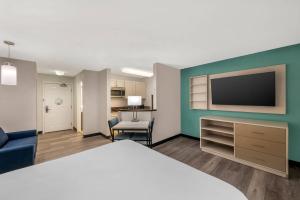a hotel room with a bed and a flat screen tv at MainStay Suites Sterling near Dulles Town Center in Sterling