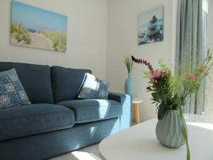 a living room with a couch and a table with a vase of flowers at Stunning apartment in Schoorl, North Hollandâ you can bike to the beach in Schoorl +55 photos