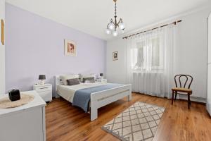 a white bedroom with a bed and a chair at Apartment Neda in Rabac - Bay View in Rabac