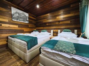 two beds in a room with wooden walls at Villa Simona in Rajecké Teplice