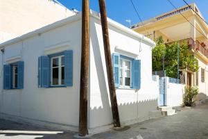 a white building with blue shutters and a pole at Yiayias House in Aegina Town