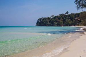 a beach with the ocean and trees in the background at Rocky Jungle Bungalows in Koh Rong