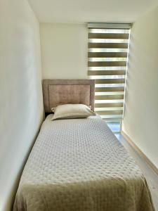 a bed in a white room with a window at Lindo apartamento en excelente zona Central Urban Mzles in Manizales