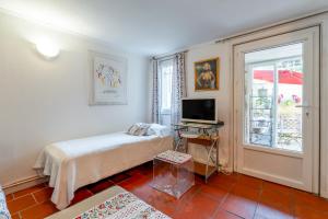 a bedroom with a bed and a tv and a window at La Ruche des Abeilles in Avignon
