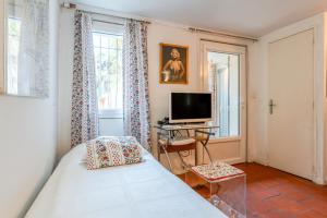 a bedroom with a bed and a television and a window at La Ruche des Abeilles in Avignon
