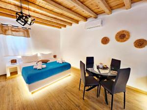 a bedroom with a blue bed and a table and chairs at Mykonian Breeze in Ano Mera +43 photos