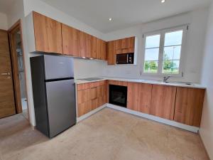 an empty kitchen with wooden cabinets and a stainless steel refrigerator at Gite des Polders in Saint-Quentin-en-Tourmont