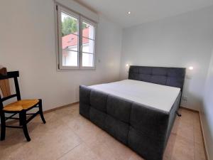 a bed in a room with a chair and a window at Gite des Polders in Saint-Quentin-en-Tourmont