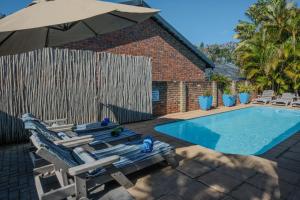 a swimming pool with two lounge chairs and an umbrella at Marlin Lodge St Lucia in St Lucia