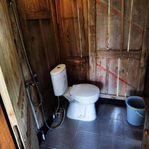 a bathroom with a toilet in a wooden wall at Homestay Ijen Lemon House in Jambu