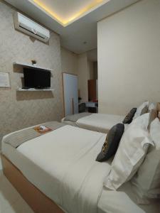 a hotel room with two beds and a television at Mutu Edutel in Panggungrejo