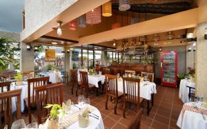 a restaurant with white tables and chairs and a bar at Bronam Residence & Spa in Phumi Ta Phul