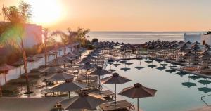 a resort with a pool with umbrellas and the ocean at Blue Sea Island in Kolimbia