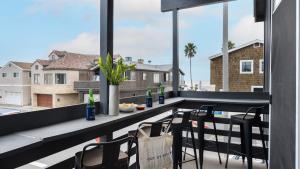 a balcony with a table and chairs and a window at Sleeps 18 Steps to the Beach Shops Eateries Ocean Views Patio Fire Pit in Newport Beach