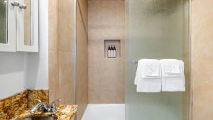 a bathroom with a shower with a sink and towels at Sleeps 18 Steps to the Beach Shops Eateries Ocean Views Patio Fire Pit in Newport Beach +53 photos