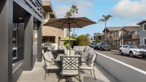 a table and chairs on a balcony with an umbrella at Sleeps 18 Steps to the Beach Shops Eateries Ocean Views Patio Fire Pit in Newport Beach